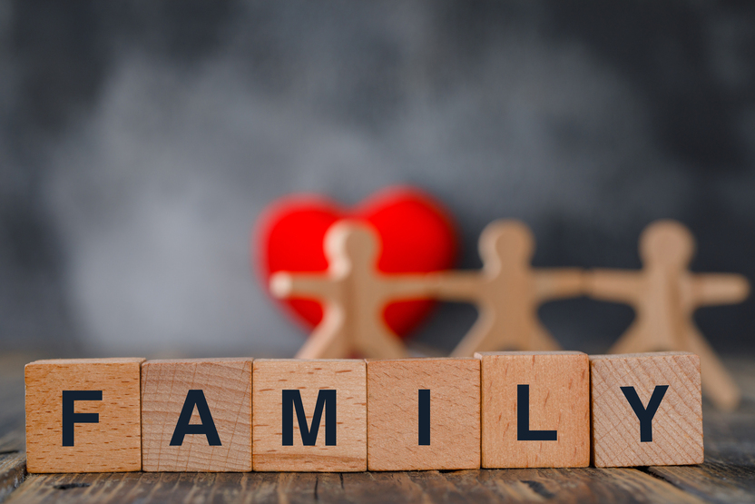 Houten blokken met het woord family en figuren van een gezin op de achtergrond.