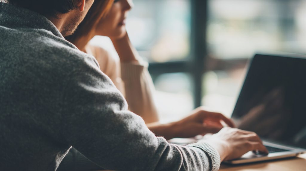 Twee collega's werken geconcentreerd samen achter een laptop in een lichte, moderne werkomgeving